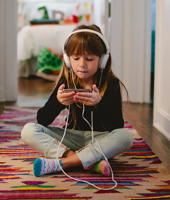 Young girl on floor looking at her phone. 
